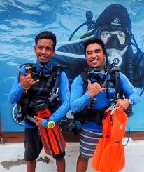 Scuba diving trainers holding equipment while preparing students for open water training